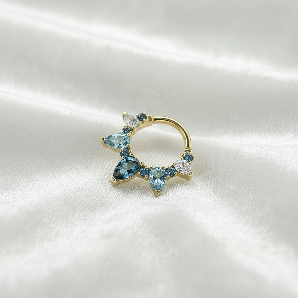 Clicker in Soliden Echtgold mit fein gefassten runden Diamanten in kristallklar, london blue und einem blauen großen Topas in Pear-Shape mittig platziert.